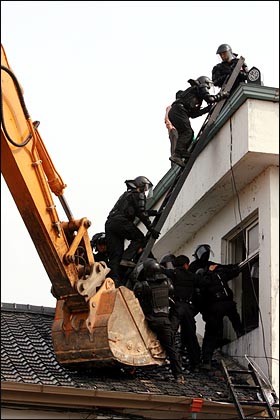 경찰이 분교 옥상에서 농성중인 시위대를 끌어내기 위해 지붕위에 포크레인과 사다리를 이용한 경찰특공대 투입을 시도하고 있다.
 